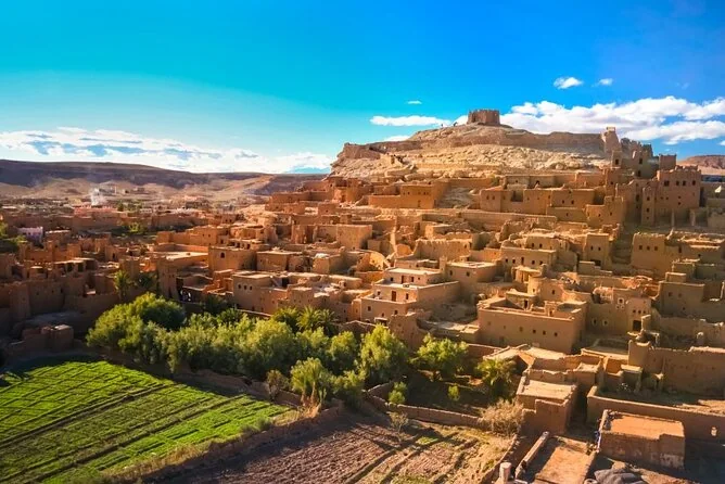 Mud-brick village above green fields and palm groves
